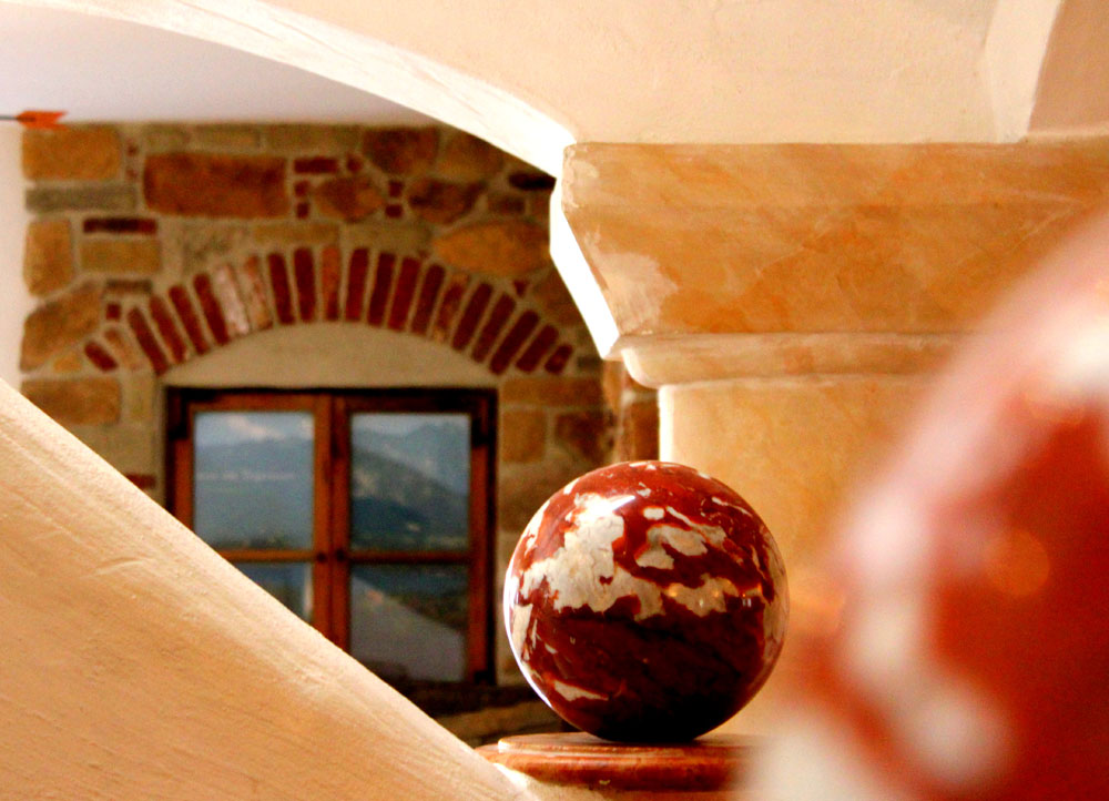 Erdgeschoss Dekorative Kugel auf einem Sockel vor einem Fenster mit gemauertem Rundbogen in warmem Licht.