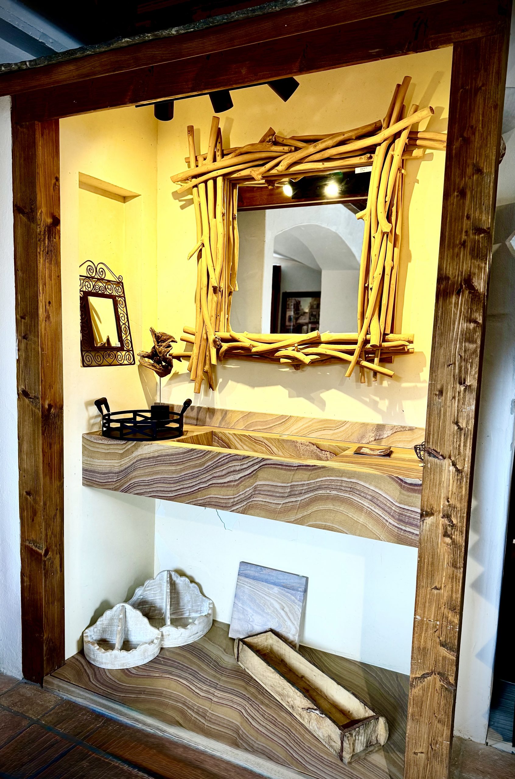 Ein Musterwaschtisch aus Naturstein Rainbow. Spiegel mit Rand aus Ästen geflochten.